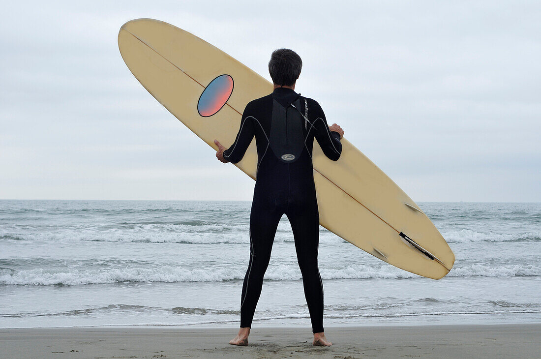 Mann mit Surfbrett am Strand