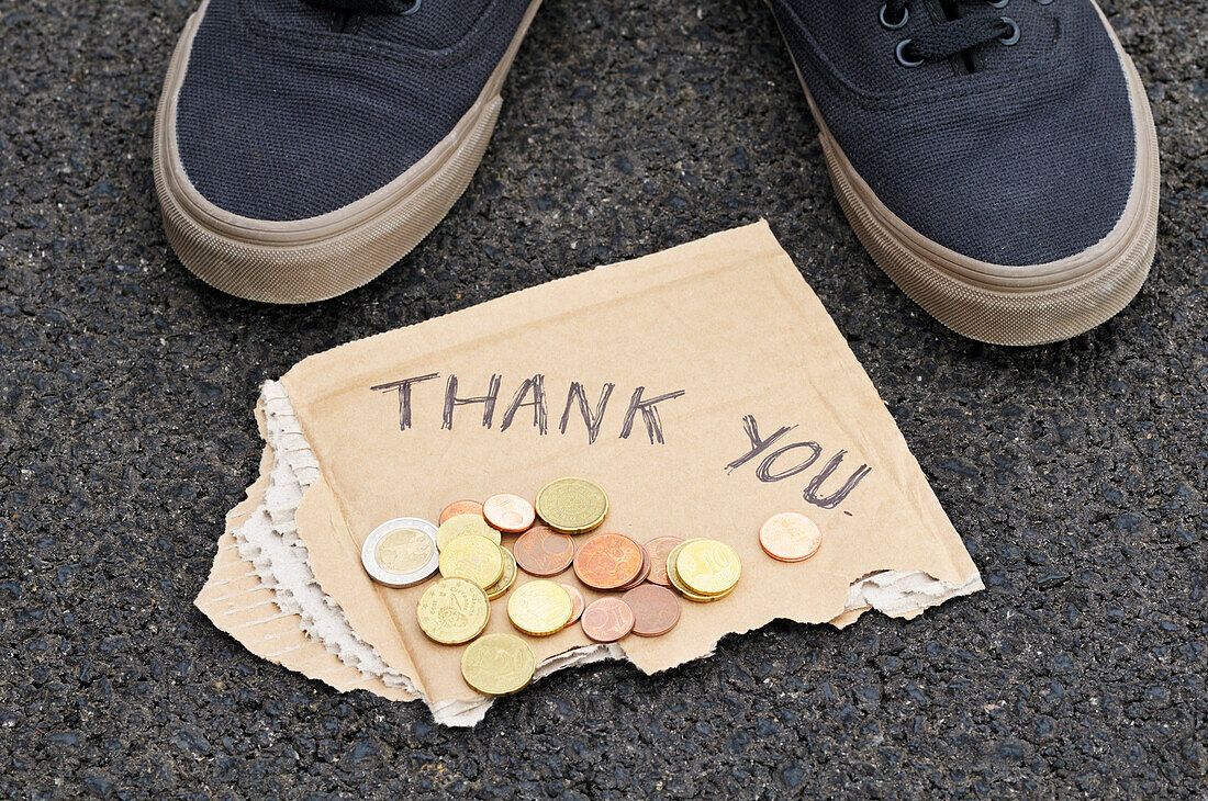 Füße mit Kleingeld und Dankeschön-Schild