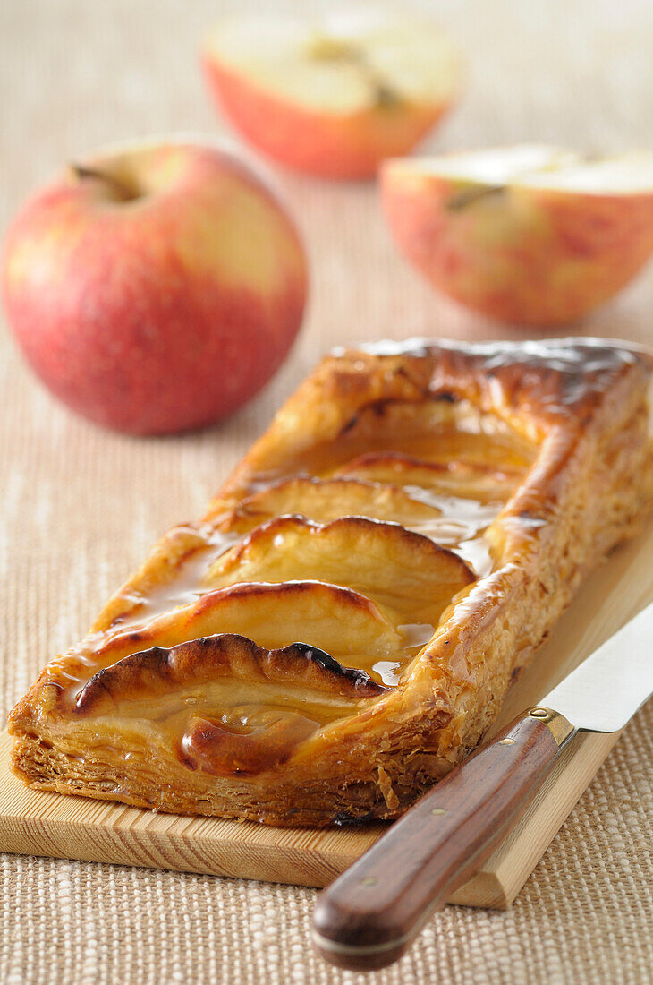 Close-up of Apple Tart with Knife on Cutting Board with Apples in background,Studio Shot