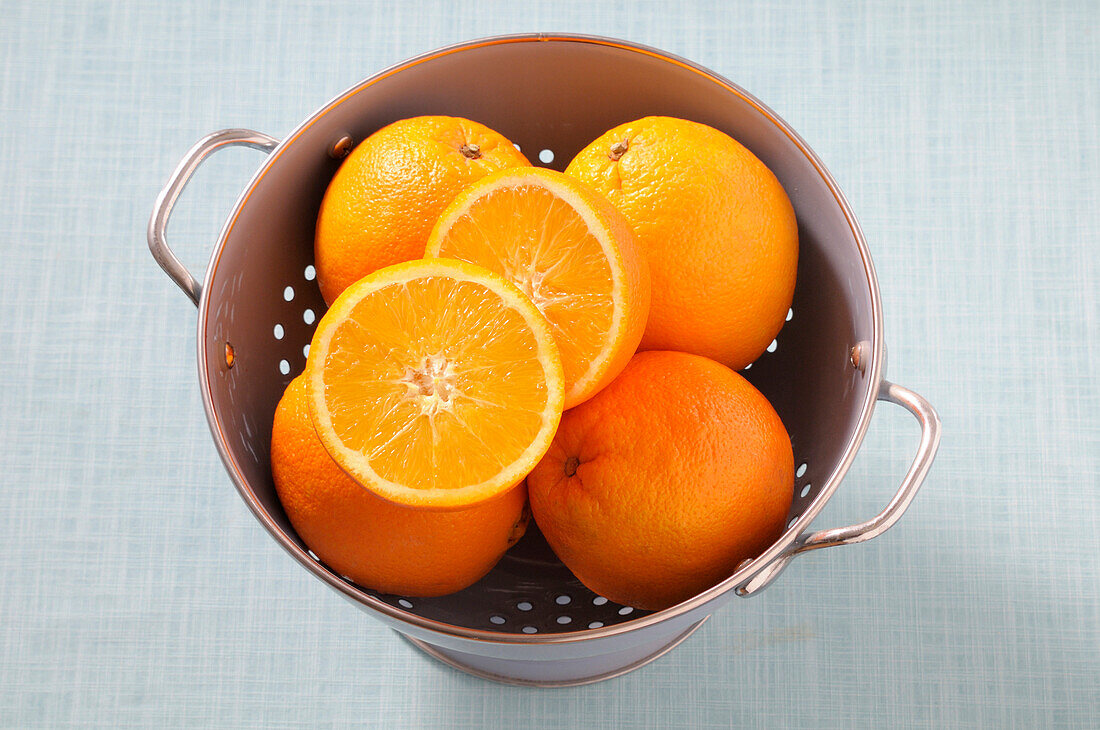 Overhead View of Oranges in Colander on Blue Background,Studio Shot