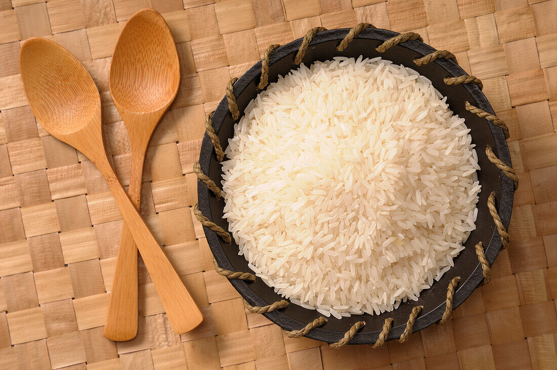 Draufsicht auf eine Schüssel mit weißem Reis mit Holzlöffeln
