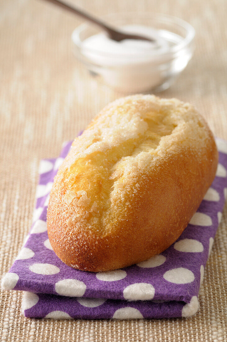 Nahaufnahme von Brioche mit Zucker auf gepunkteter Serviette