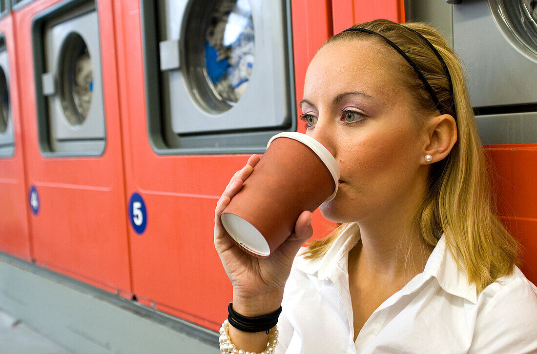 Frau trinkt Kaffee im Waschsalon