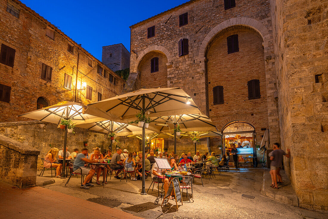Blick auf ein Restaurant im historischen Zentrum in der Abenddämmerung, San Gimignano, UNESCO-Welterbe, Provinz Siena, Toskana, Italien, Europa