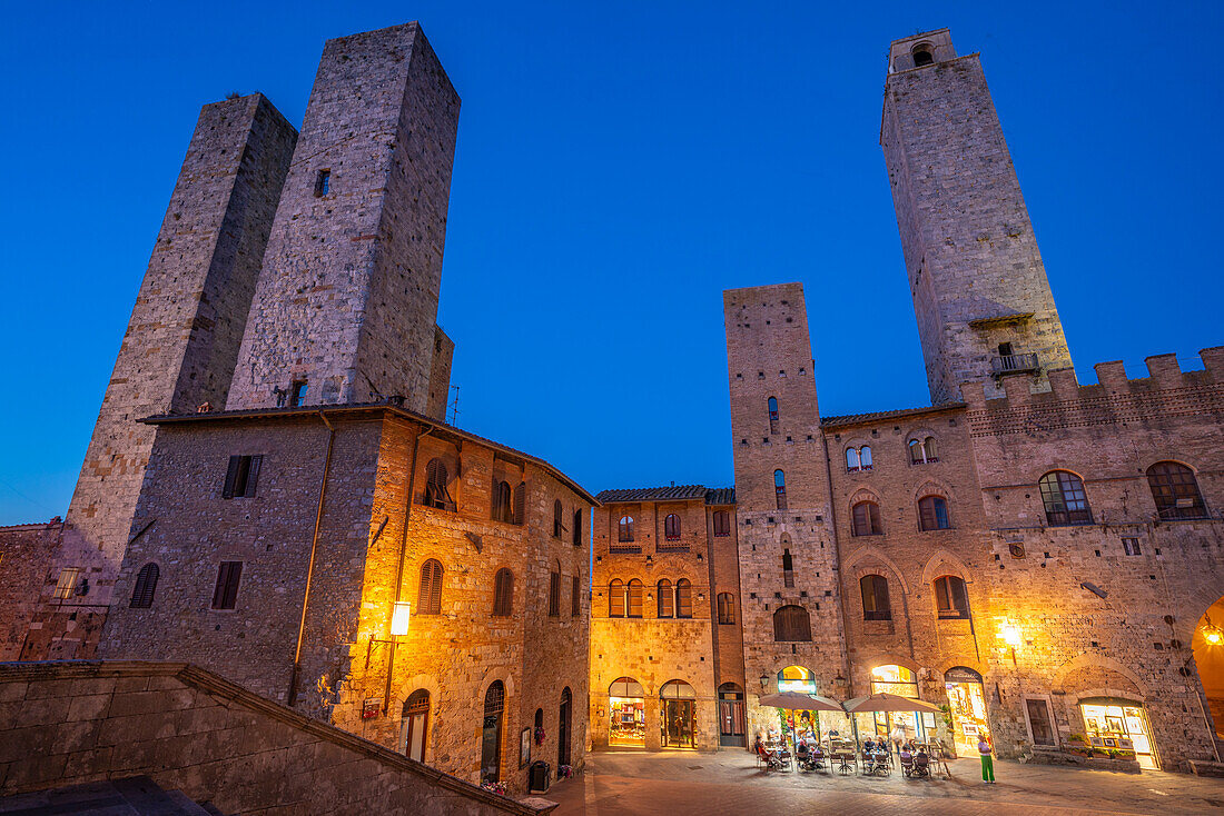 View of restaurants in Piazza del Duomo at dusk,San Gimignano,UNESCO World Heritage Site,Province of Siena,Tuscany,Italy,Europe