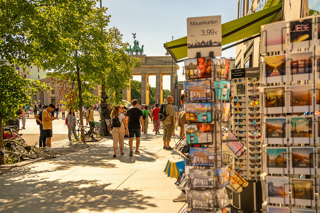 Blick auf das Brandenburger Tor, Postkarten und Besucher auf dem Pariser Platz an einem sonnigen Tag,Mitte,Berlin,Deutschland,Europa