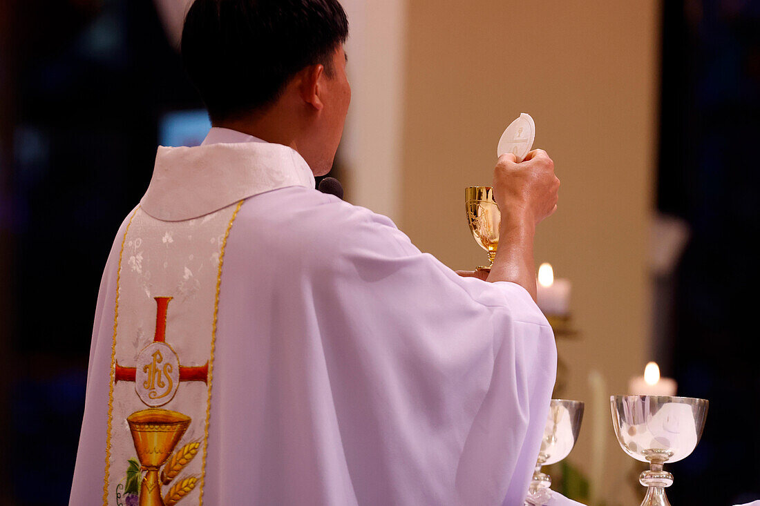 Back view of Priest with chasuble at Eucharist celebration,Sunday Mass,Elevation of the Host,St. Nicholas Cathedral,Dalat,Vietnam,Indochina,Southeast Asia,Asia