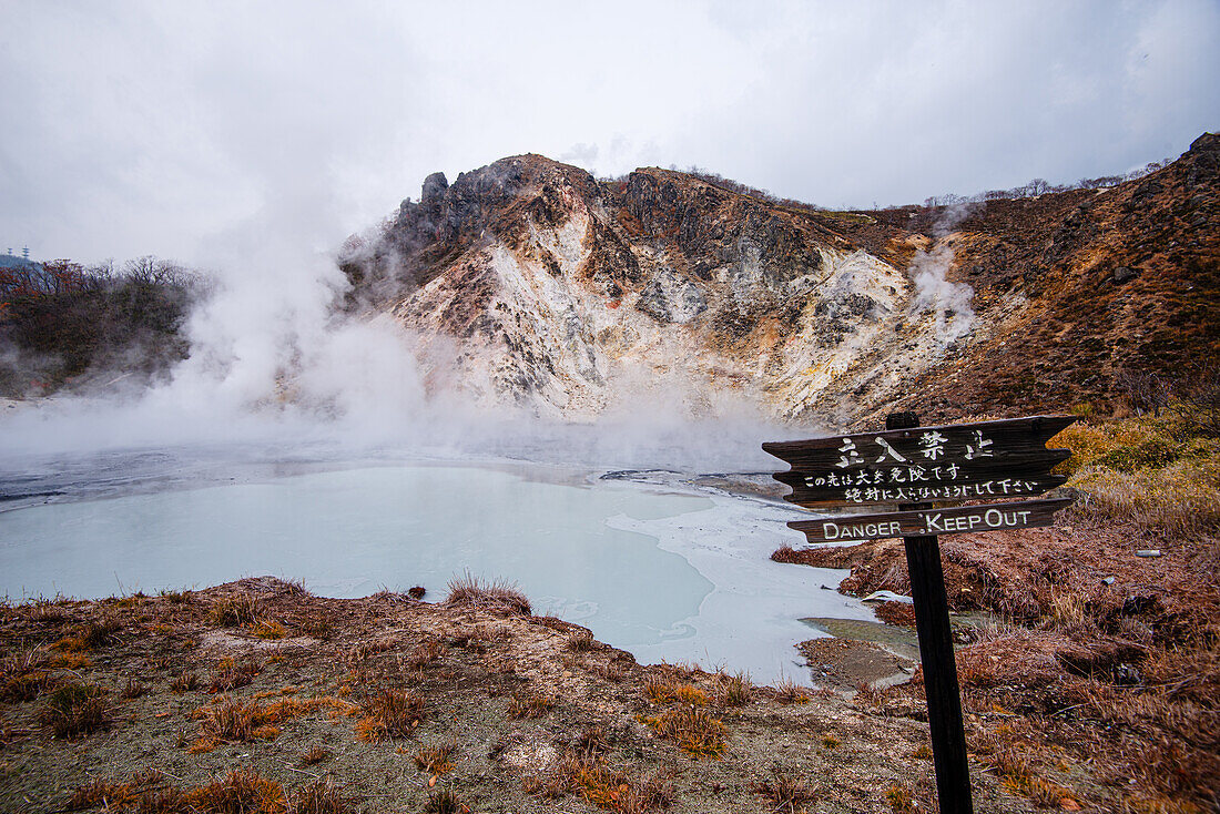 Danger sign in front of volcanic field and steaming pond in Noboribetsu,Hell Valley,Hokkaido,Japan,Asia