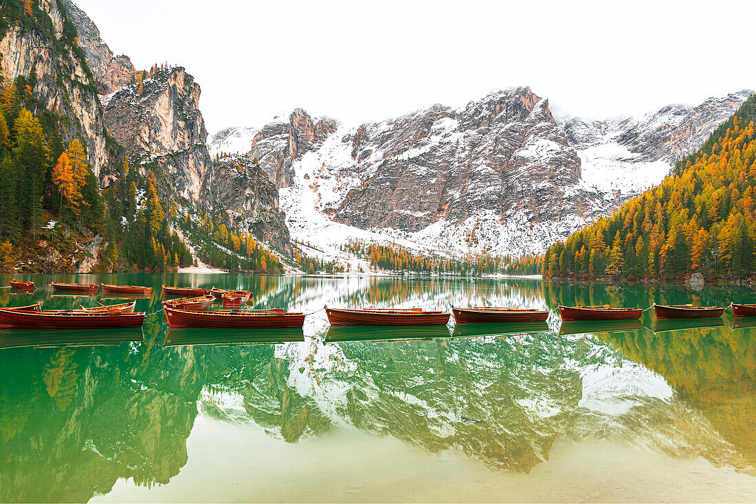 Holzboote schwimmen auf dem ruhigen Wasser des Pragser Wildsees, Herbstansicht, Prags, Südtirol, Provinz Bozen, Italien, Europa