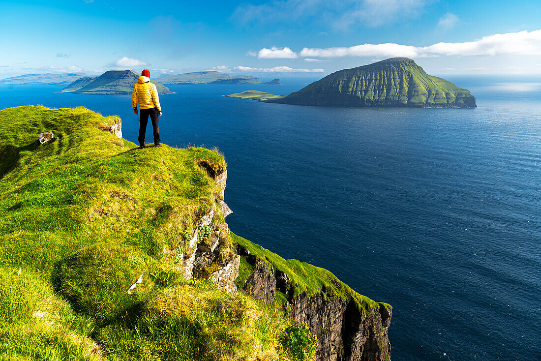Wanderer steht oben auf einer Klippe und bewundert die schroffe Aussicht, Nordradalur, Insel Streymoy, Färöer Inseln, Dänemark, Europa