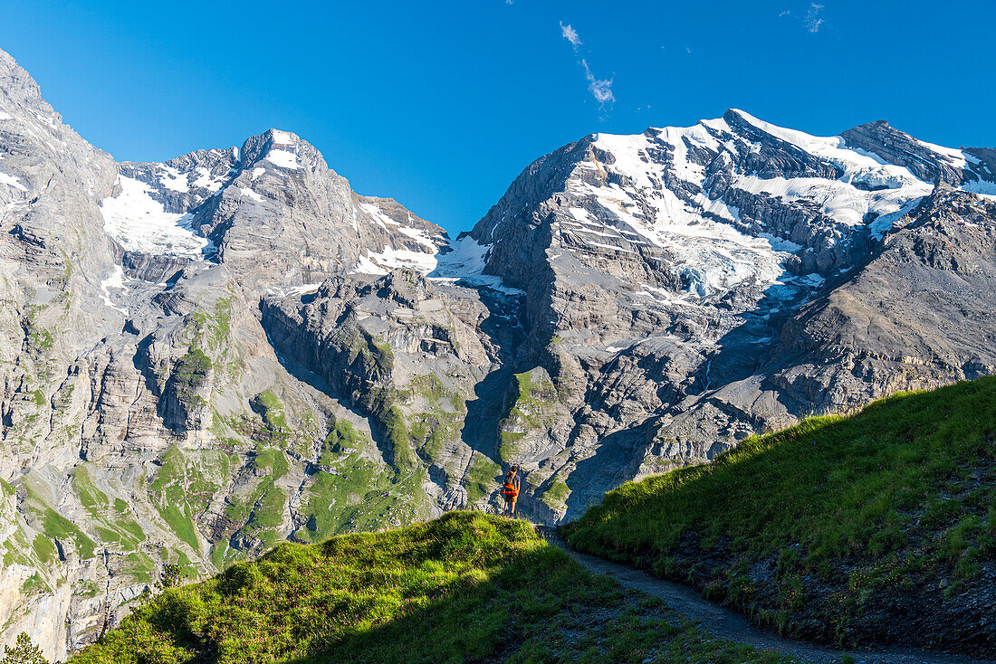 Hiker walks the summer trail surrounded by Swiss glacier,Oeschinensee,Kandersteg,Bern Canton,Switzerland,Europe