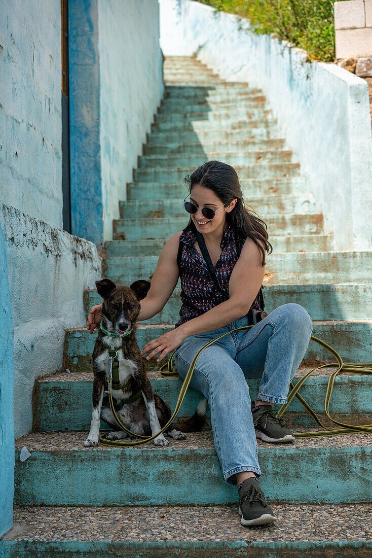 Frau mit Hund auf blauen Stufen sitzend, Juzcar, Region Pueblos Blancos, Andalusien, Spanien, Europa