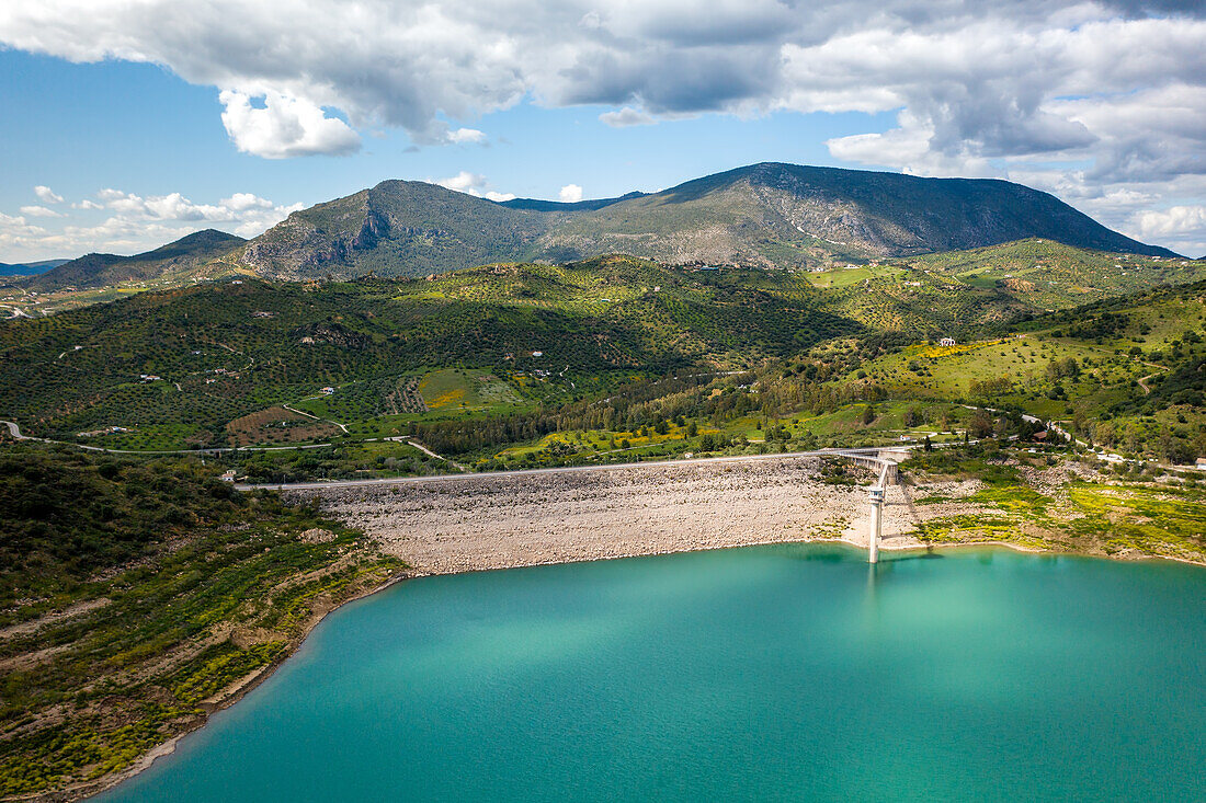 Drone aerial view of Zahara de la Sierra water reservoir dam with turquoise water and mountains in the background,Andalusia,Spain,Europe