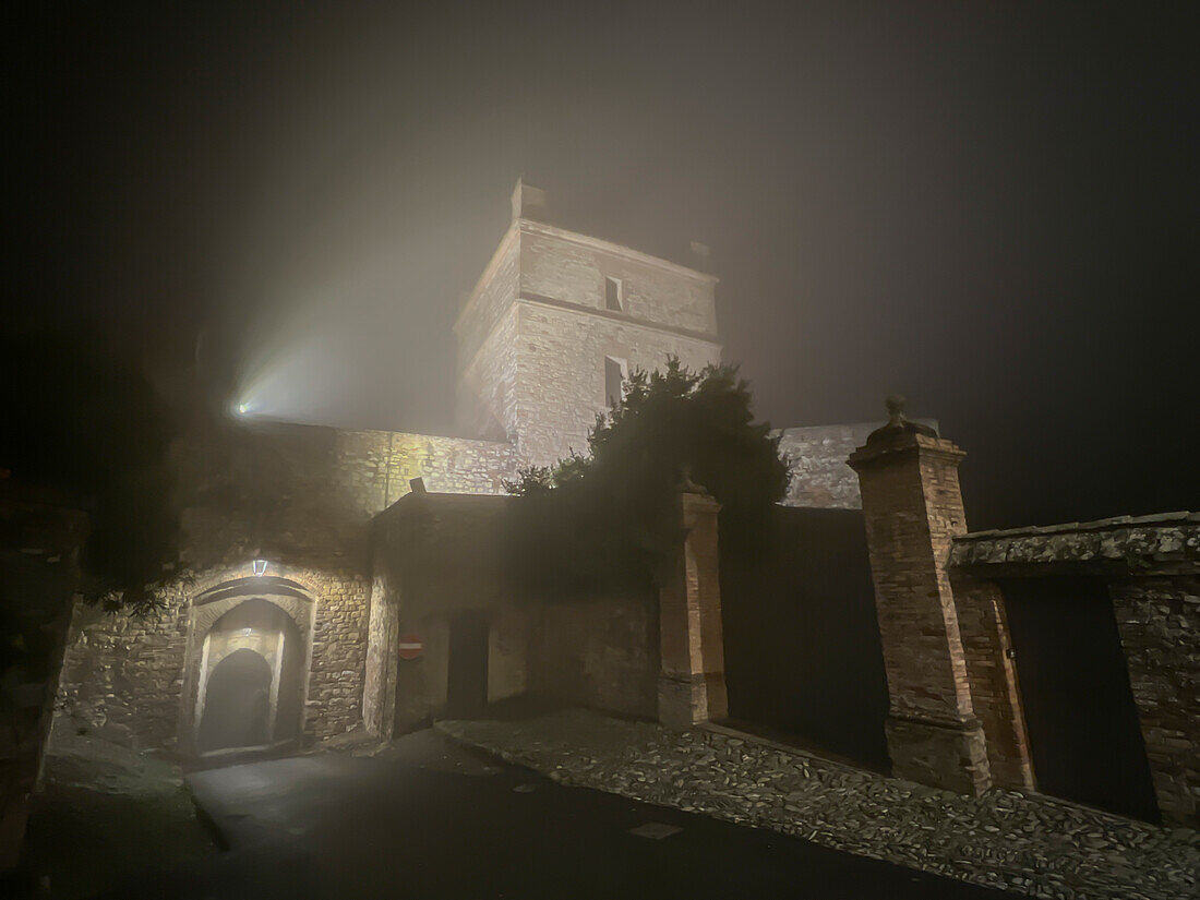 Der Turm und das Tor einer mittelalterlichen Burg in einer kleinen Stadt in einer Winternacht mit Nebel, Castello di Seravalle, Emilia Romagna, Italien, Europa
