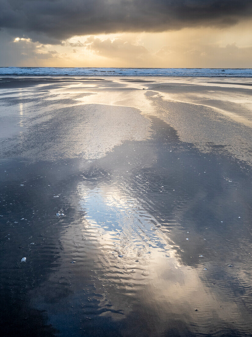 Regenwolken und Spiegelungen am Strand von Rhossili bei Sonnenuntergang mit dem Schiffswrack der Helvetia, Rhossili, Gower, Südwales, Vereinigtes Königreich, Europa