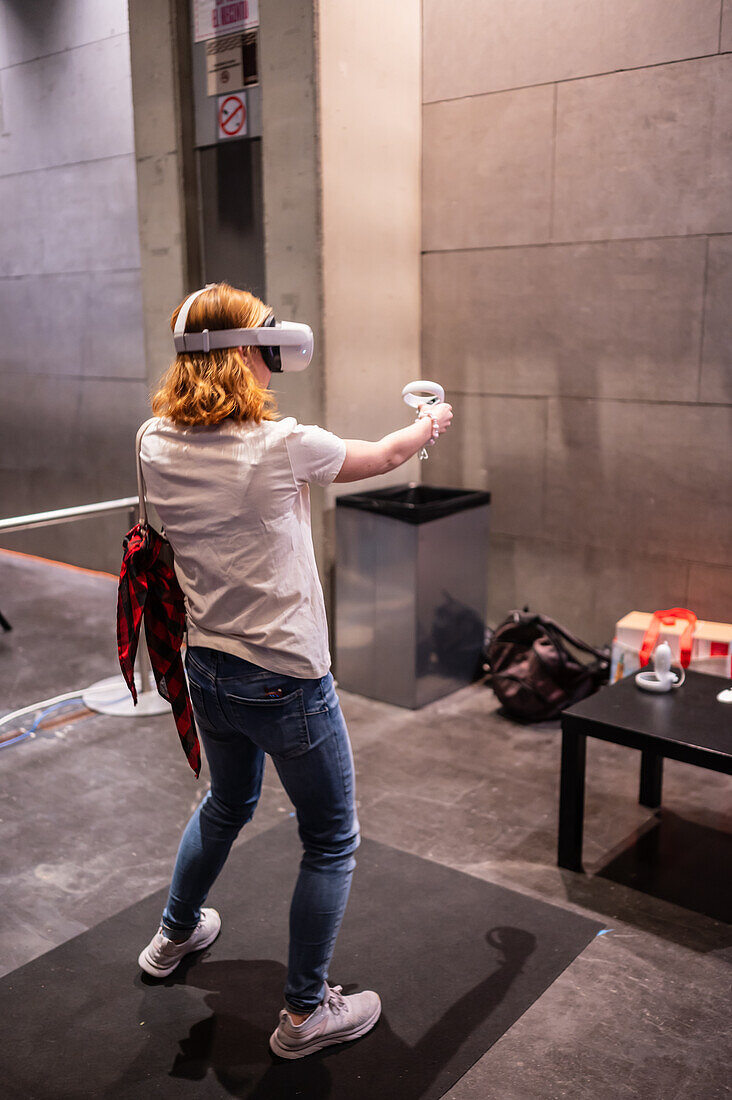 Junge Frau spielt mit dem Meta Quest 2 All-in-One VR-Headset während des ZGamer, einem Festival für Videospiele, digitale Unterhaltung, Brettspiele und YouTuber während der El Pilar Fiestas in Zaragoza, Aragonien, Spanien