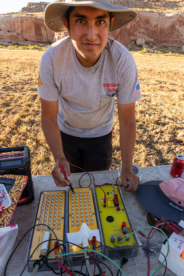 A technician demonstrates electrical triggers or controllers for fireworks launchers for a fireworks show in a field in Utah.