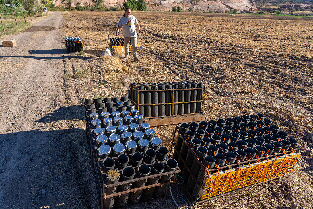 A technician sets up a battery of launchers for 4" pyrotechnic shells being prepared for a fireworks show in a field in Utah.