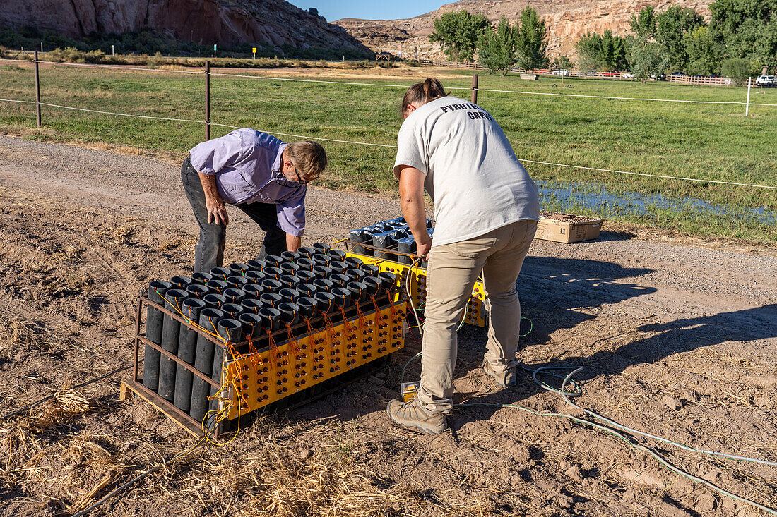 Technicians set up a battery of launchers for 4" pyrotechnic shells being prepared for a fireworks show in a field in Utah.