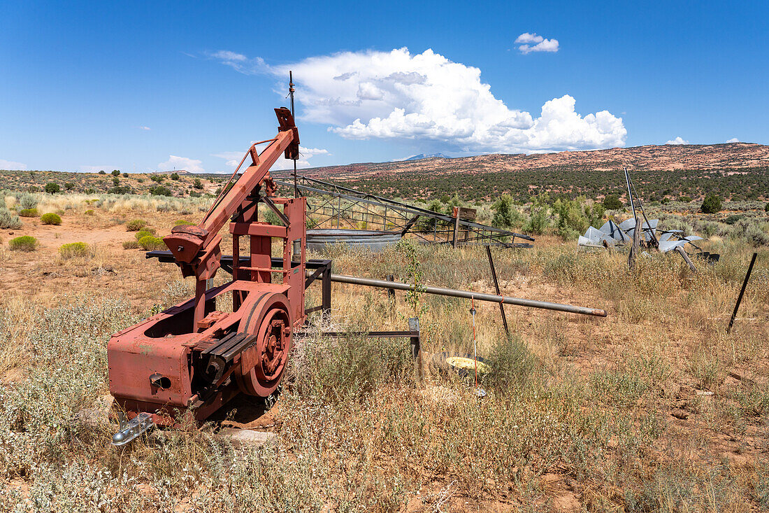 An old mechanical pump on water well on a former cattle ranch in southeastern Utah. Behind is a collapsed windpump or windmill.