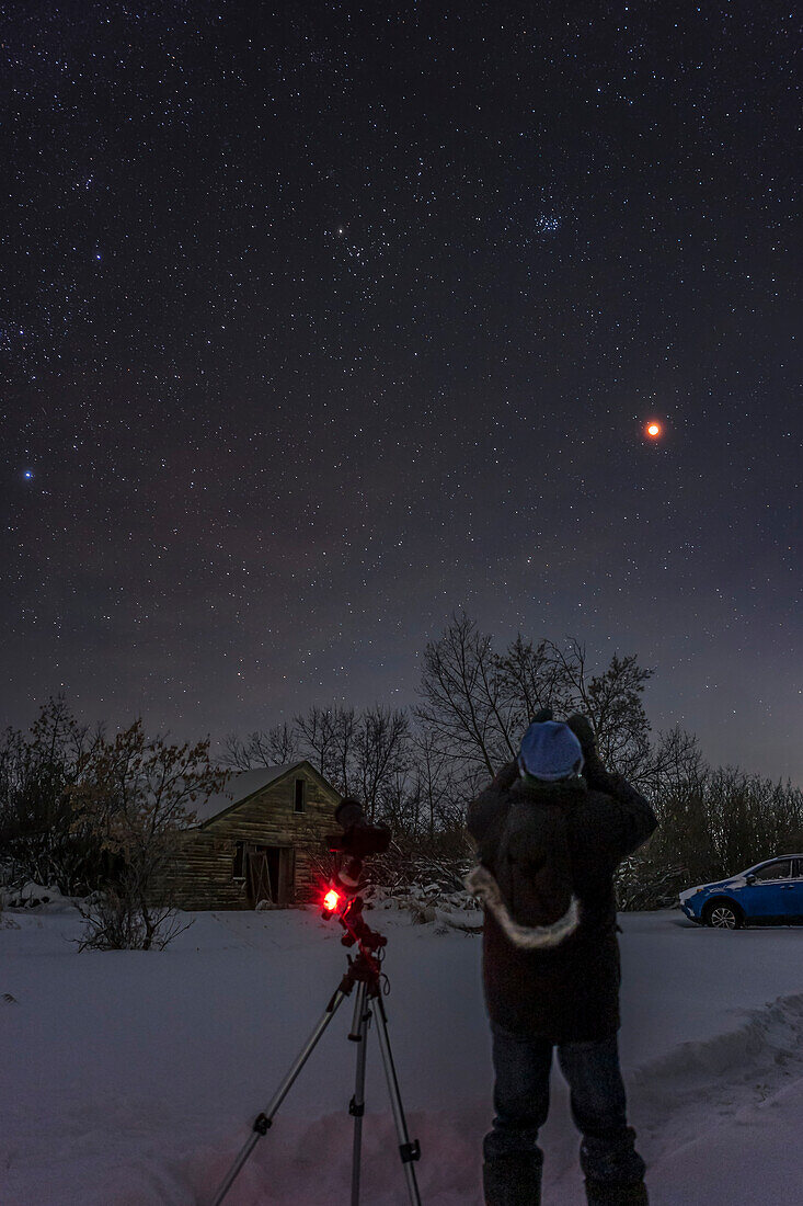 Ein Selbstporträt von mir bei der Beobachtung der totalen Mondfinsternis am 8. November 2022, an einem sehr kalten (-25° C) Morgen um 4 Uhr. Über dem roten Mond sind die Sterne des Stieres zu sehen, darunter die Sternhaufen Hyaden und Plejaden.