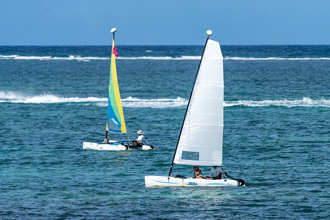 Hobie Cat catamaran sailboats sailing in the Caribbean Sea at San Pedro on Ambergris Caye in Belize. The wave break at the Belize Barrier Reef is visible behind.