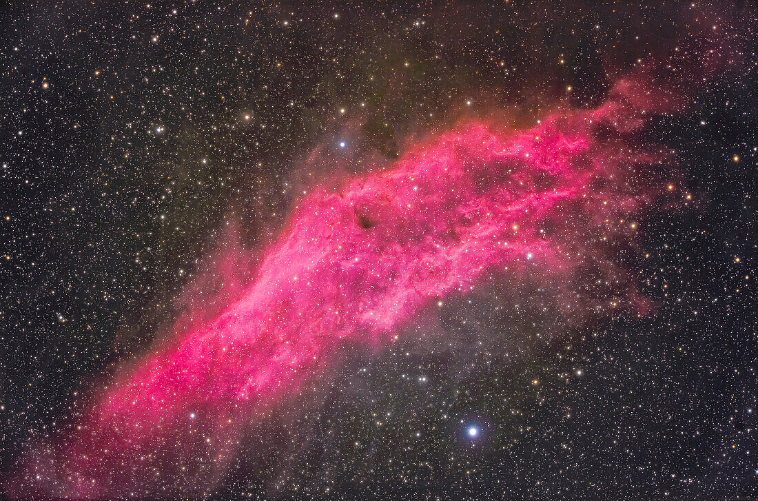 Dies ist der Kaliforniennebel, auch bekannt als NGC 1499, im Perseus in der Nähe des Sterns Menkib oder Xi Persei, unten. Obwohl es sich in erster Linie um einen Emissionsnebel handelt, befindet sich in der Peripherie Staub, der einen schwachen Reflexionsnebel bildet. Der Hauptnebel strahlt nicht nur in der roten H-Alpha-Wellenlänge, sondern auch in der blau-grünen H-Beta-Wellenlänge stark, daher die rosa oder magentafarbene Färbung.
