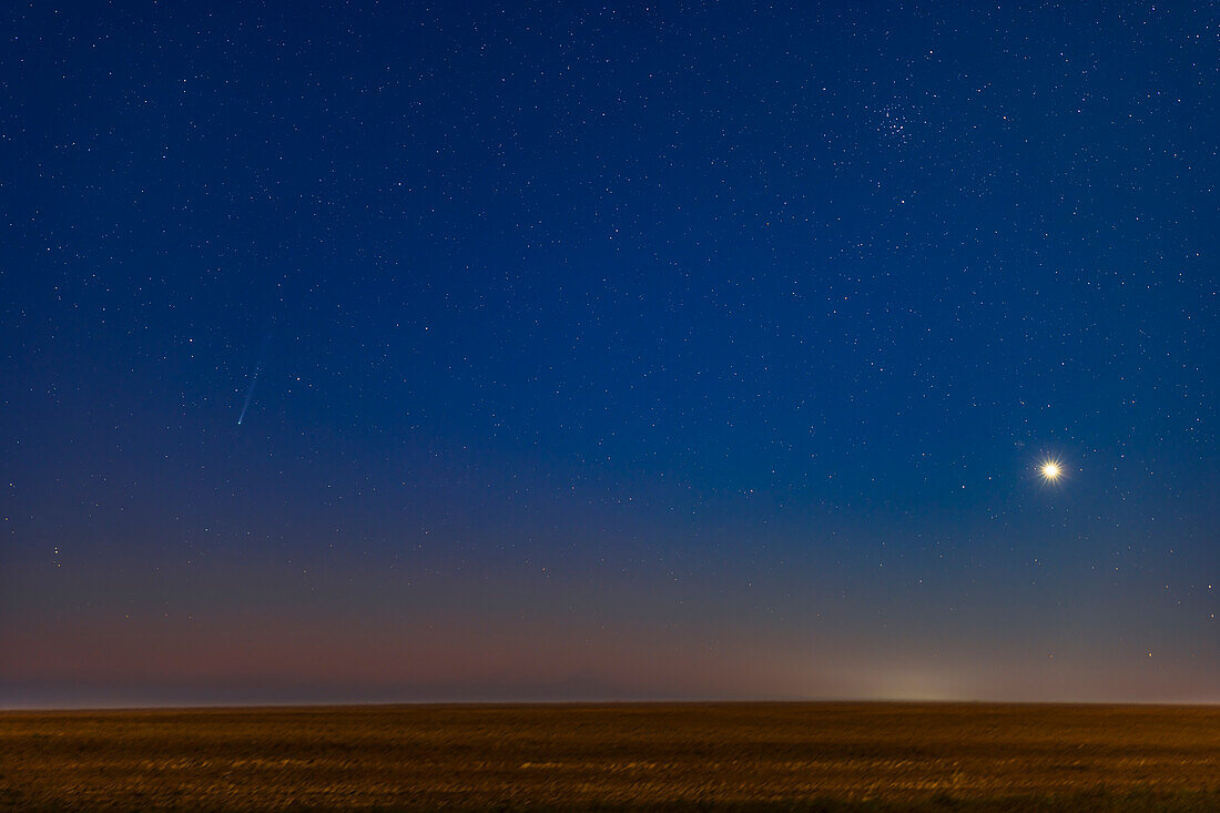 Comet Nishimura (C/2023 P1),at left,captured at dawn on September 7,2023 with the sky beginning to brighten with morning twilight colours. Plus the last quarter Moon was lighting the sky and landscape with moonlight. The comet appears with Venus,at right,beginning its morning sky appearance for 2023/24. In addition,the star cluster Messier 44,the Beehive,is at top right. The smaller Messier 67 star cluster is just above Venus.