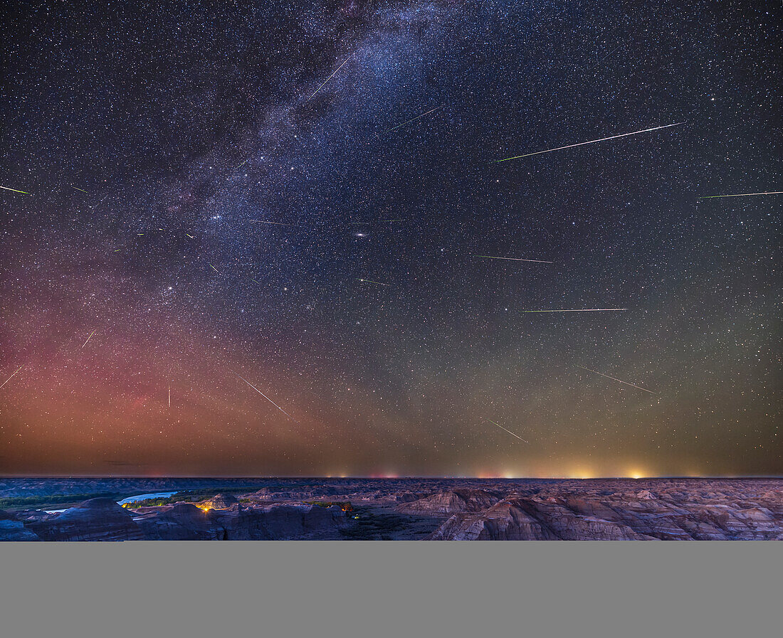 This is the Perseid meteor shower over the badlands of Dinosaur Provincial Park,in the Red Deer River valley in Alberta,with the summer sky above filled with about two dozen meteors from the annual shower on August 12,2023. The meteors all appear to be streaking away from the radiant point in Perseus at left,below the "W" of Cassiopeia. The meteor trails are shortest near the radiant point,as at that location they are coming at us head on. The Andromeda Galaxy is near centre.