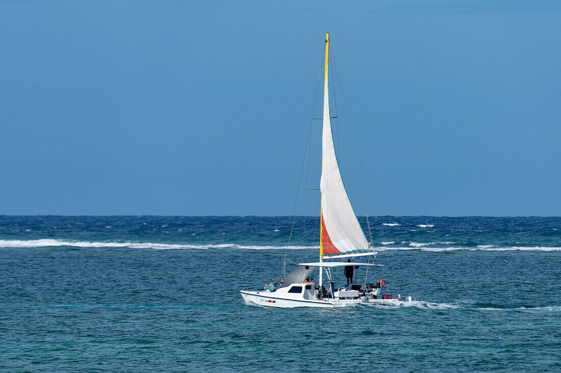 A catamaran sailboat on a sailing tour in the Caribbean Sea at San Pedro on Ambergris Caye in Belize. The wave break at the Belize Barrier Reef is visible behind.