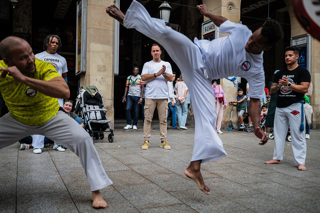 Mitglieder der Mestre Branco Capoeira Escola demonstrieren auf der Straße während der Fiestas de El Pilar in Zaragoza, Aragonien, Spanien