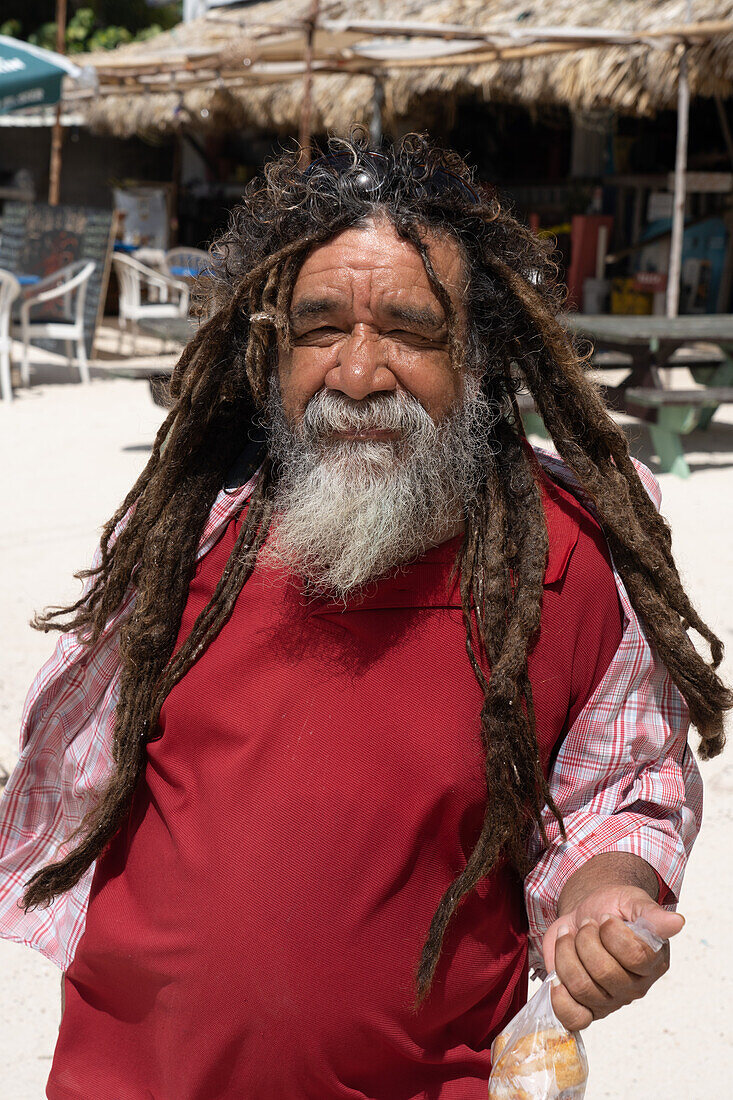 Ein älterer belizianischer Mann mit Bart und Dreadlocks am Strand von San Pedro auf der Karibikinsel Ambergris Caye, Belize.