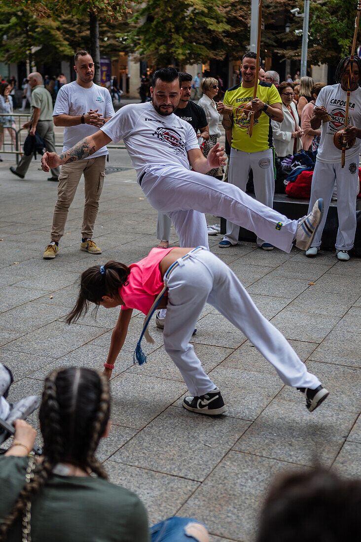 Mitglieder der Mestre Branco Capoeira Escola demonstrieren auf der Straße während der Fiestas del Pilar in Zaragoza, Aragonien, Spanien