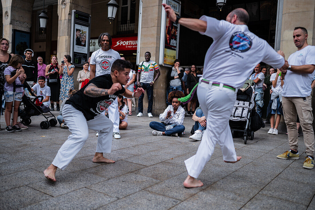 Mitglieder der Mestre Branco Capoeira Escola demonstrieren auf der Straße während der Fiestas de El Pilar in Zaragoza, Aragonien, Spanien