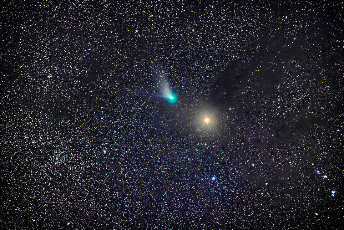 Comet C/2022 E3 (ZTF) passing Mars in the constellation of Taurus on the night of Feb 10,2023. Mars appears to be at the tip of a dark lane of interstellar dust in the Taurus Dark Clouds. The comet is showing its whitish dust tail and blue ion tail,as well as its cyan coma from diatomic carbon emission. The star cluster at left is NGC 1746.