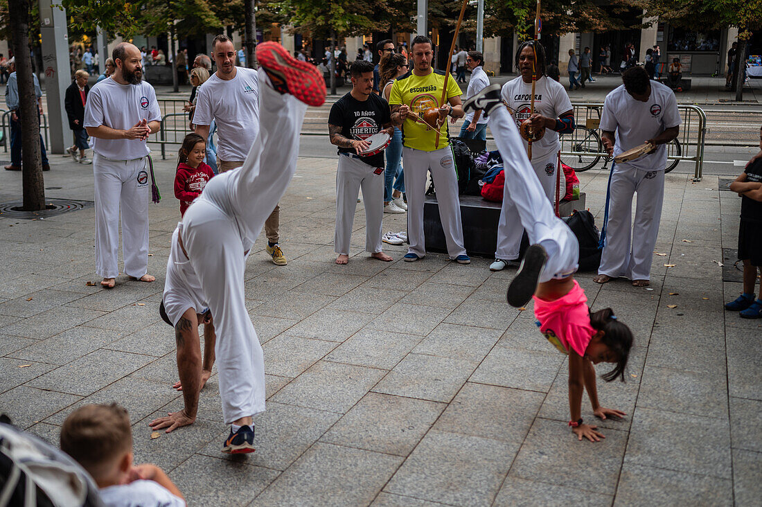 Mitglieder der Mestre Branco Capoeira Escola demonstrieren auf der Straße während der Fiestas de El Pilar in Zaragoza, Aragonien, Spanien