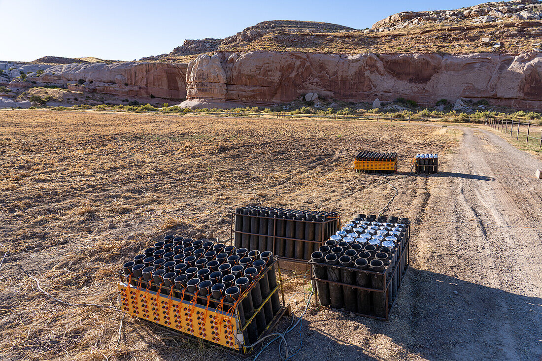 A battery of launchers for 4" pyrotechnic shells being prepared for a fireworks show in a field in Utah.