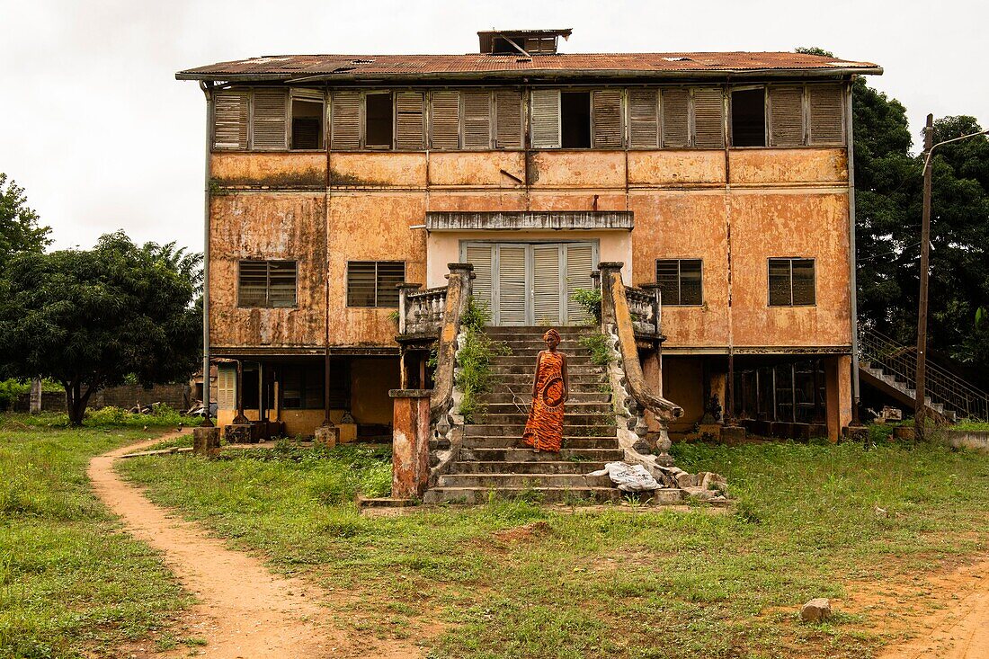 Benin, Ouidah, Frau steht vor einem alten Kolonialgebäude