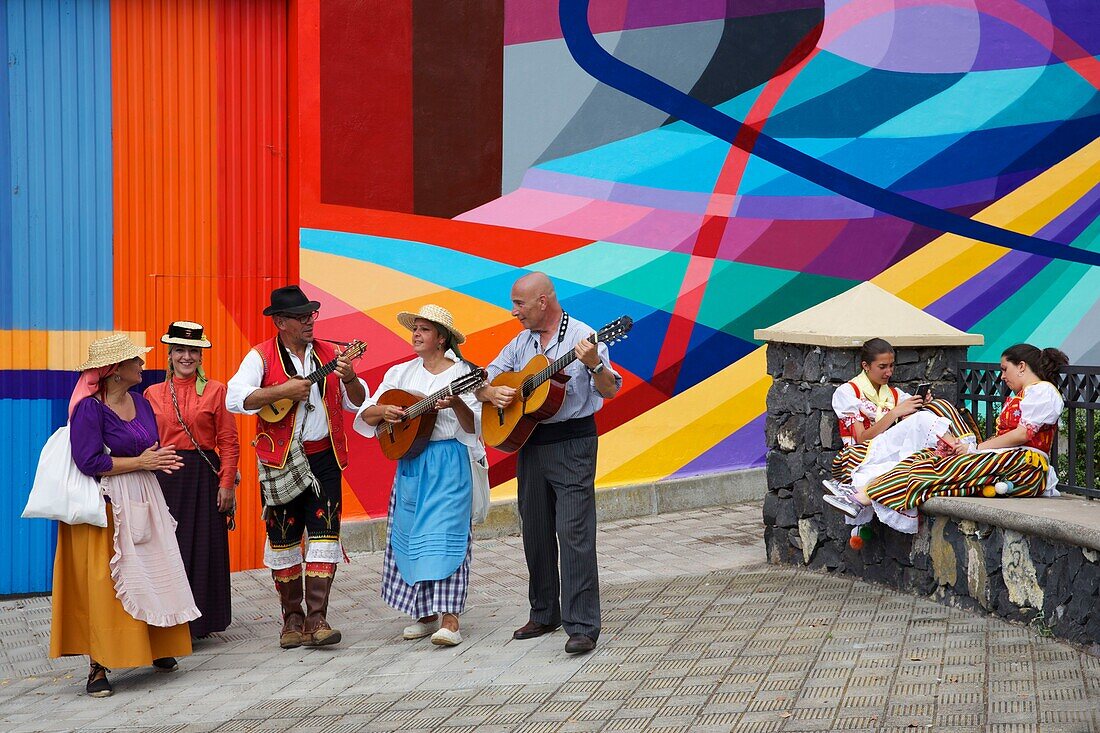 Spain, Canary Islands, Tenerife Island, group of musicians in traditional Canarian costumes in front of a wall decorated with a colorful frescoes, during a romería, a traditional celebration