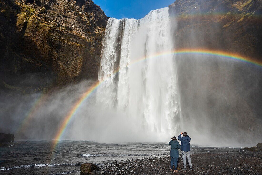 Iceland, Sudurland, Skogar, Rainbow in front of Skogafoss