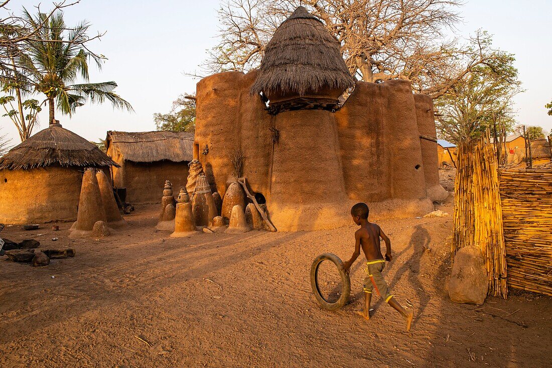 Benin, Nördlicher Distrikt, Atacora-Gebirge, Koussoukoingou, Kind spielt mit Reifen vor einem Tata aus Banco (mit Stroh vermischte Erde), traditionelles zweistöckiges Verteidigungsgebäude, typisch für Nordbenin