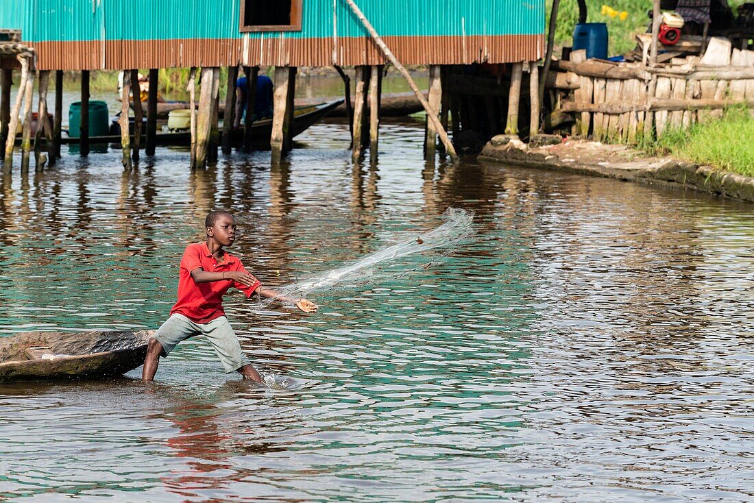 Benin, Stadt am See Ganvié, Kind wirft sein Fischernetz aus