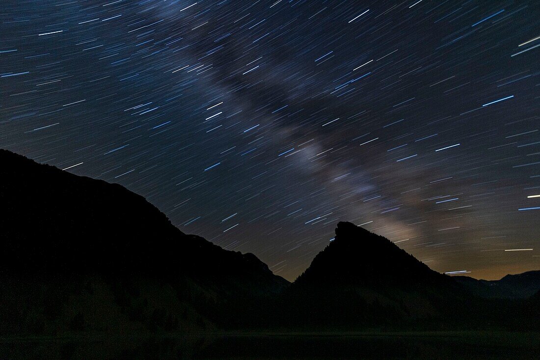 France, Alpes-de-Haute-Provence, Haute-Ubaye, Mercantour National Park, streak of circumpolar stars and the cloud of the Milky Way above the lake and the Tour des Sagnes (2364 m)