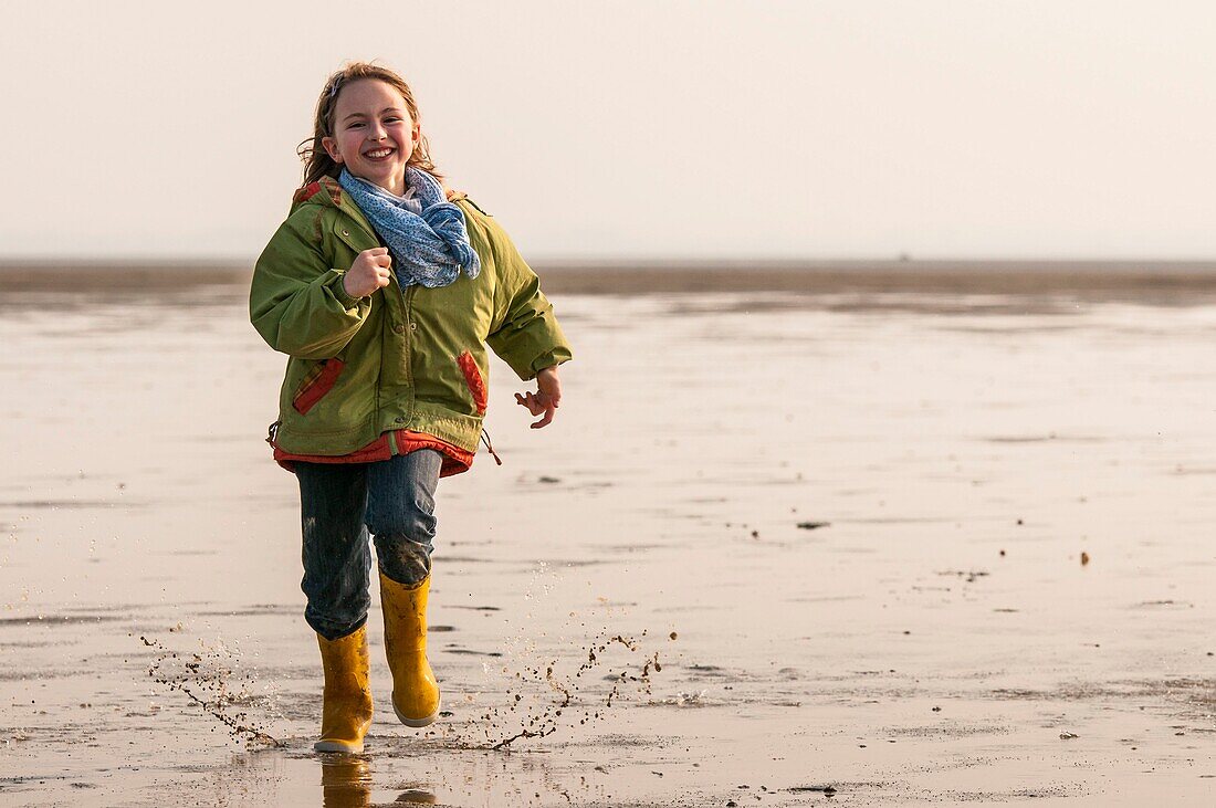 France, Somme, Baie de Somme, Le Crotoy, Child (young girl) runs with her dog (Border Collie) in Baie de Somme