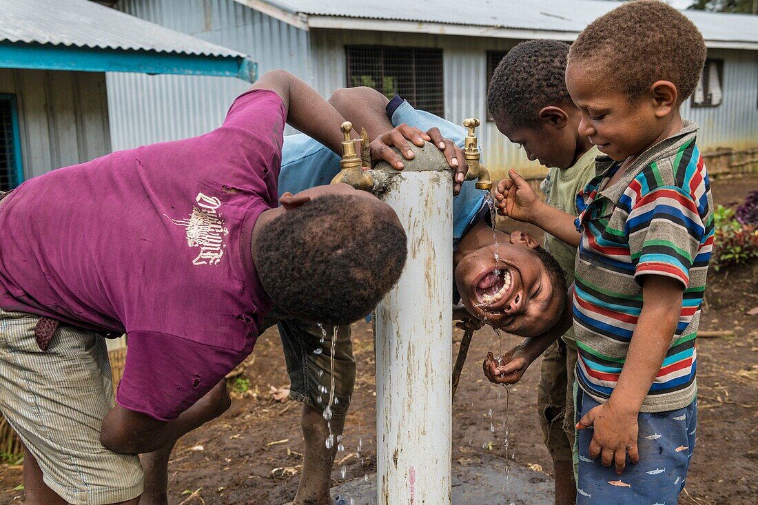 Papua New Guinea, Southern Highlands Province, Mendi, Humbra village, kids drinking from water facilities provided by United Nations