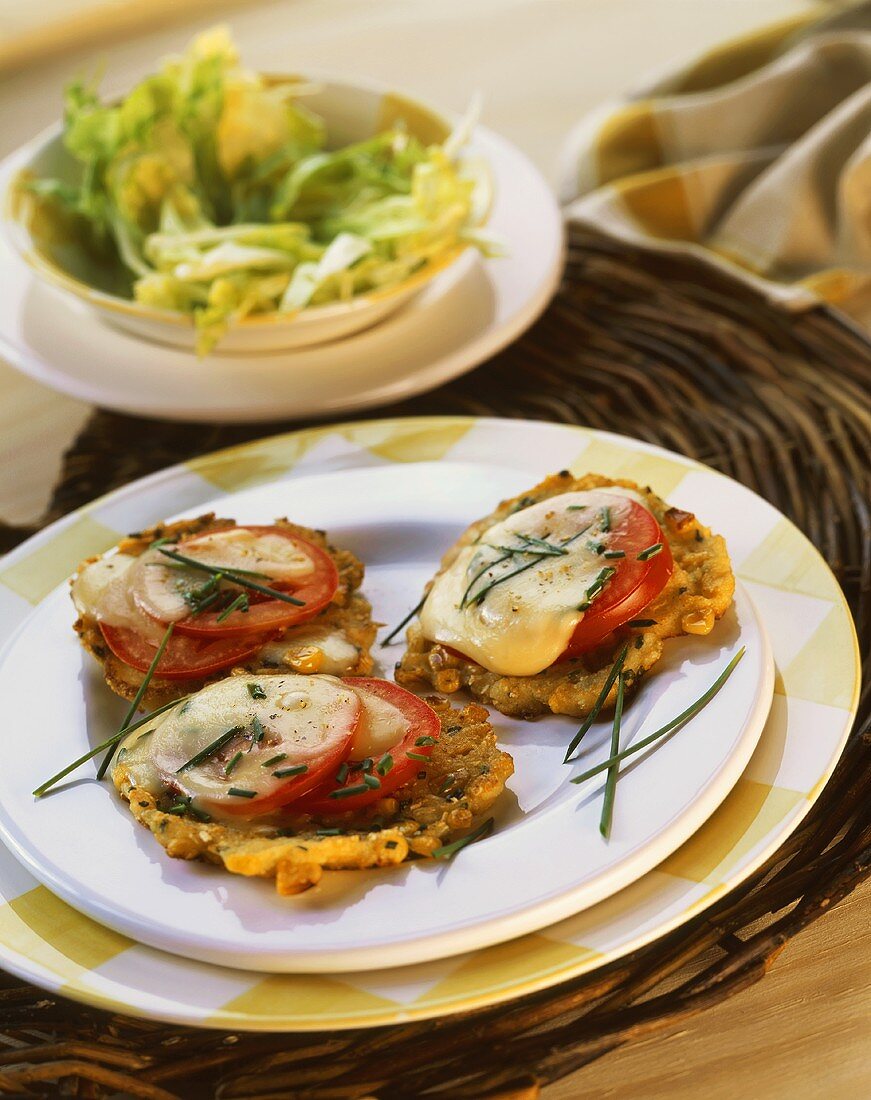 Maispuffer mit Tomaten und Käse überbacken, auf Teller