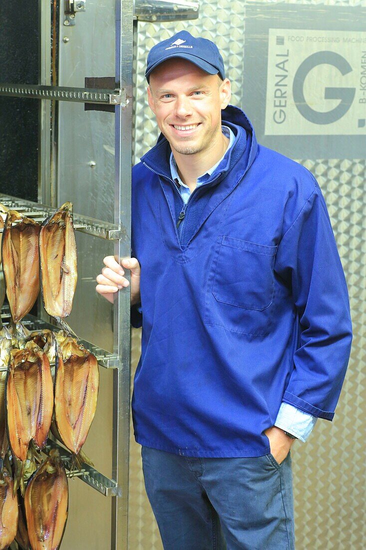 France, Pas de Calais, Boulogne sur Mer, Corrue & Deseille salting and smoking workshop, Cedric Corrue in front of a smokehouse and kipper fillets (also called red herring)