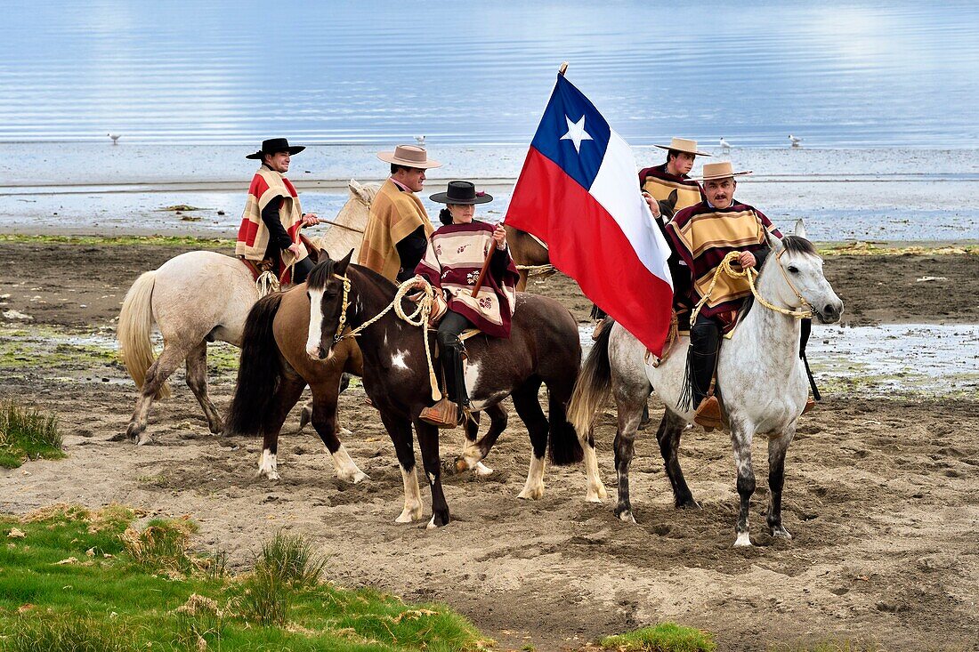 Chile,Region Los Lagos,Archipel von Chiloe,Insel Quinchao,Curaco de Velez,huasos (Reiter) mit chupalla und manta vor einer Parade,ein huaso Mädchen trägt die chilenische Flagge