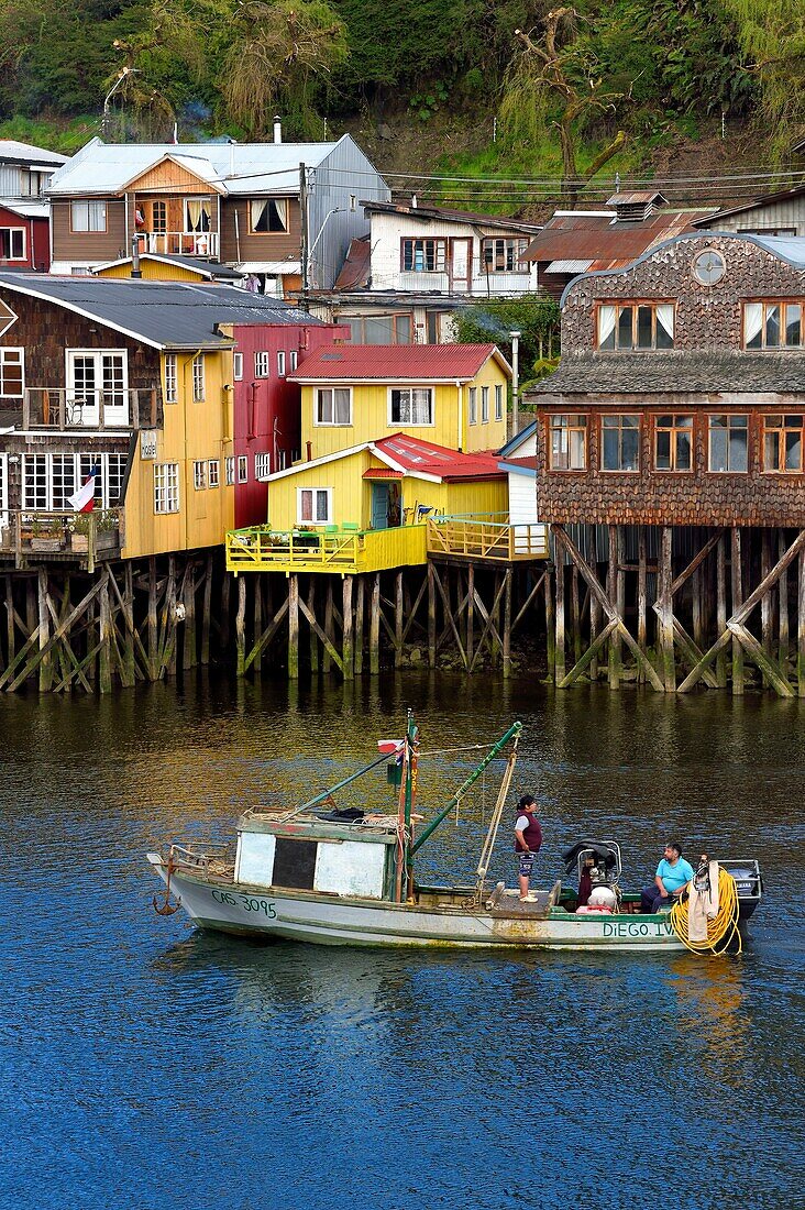 Chile, Los Lagos region, Chiloé Island, town of Castro, wooden fishing houses on stilts called palafitos in the estuary of the Gamboa River, seashell fishing boat