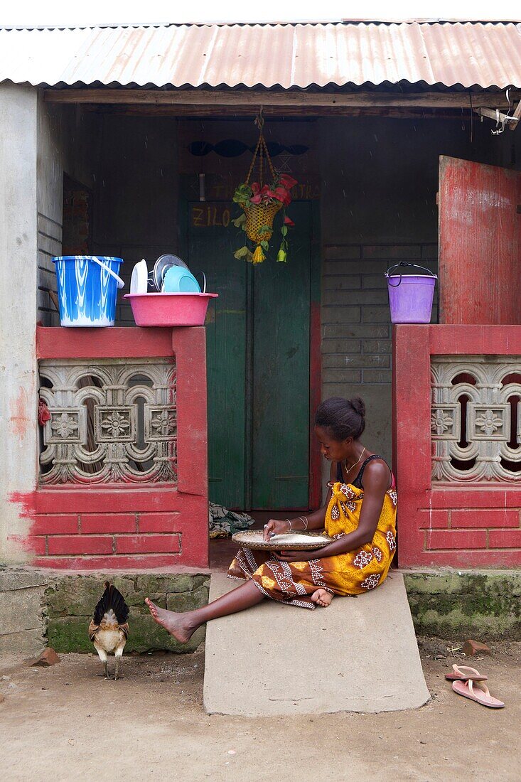 Madagaskar,Region Diana,Dorf Marosely,eine Frau sortiert Reis vor ihrem Haus